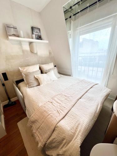 une chambre avec un lit avec des draps blancs et une fenêtre dans l'établissement Séjour parisien Suite Bastille, à Paris