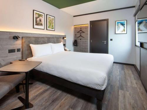 a hotel room with a large bed and a table at ibis Styles London Gatwick Airport in Crawley