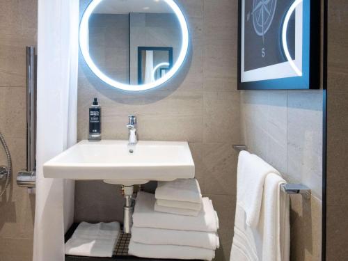 uma casa de banho com lavatório, espelho e toalhas em ibis Styles London Gatwick Airport em Crawley