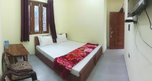 a bedroom with a bed and a table and a window at Om Pingaksh Hotel & Restaurant in Karnaprayāg