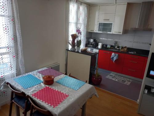 une cuisine avec une table et une cuisine avec des placards rouges dans l'établissement Appartement 2 pièces, à Puteaux