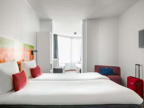 een hotelkamer met 2 bedden met rode kussens bij ibis Styles Amsterdam City in Amsterdam