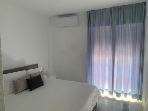 a white bedroom with a large bed and a window at Los Colimbos in Torremolinos