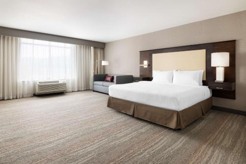 ナパにあるハンプトン イン ＆ スイーツ ナパ カリフォルニアのベッドとソファ付きの広いホテルルームです。