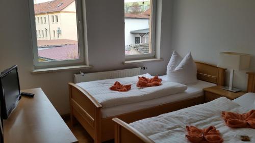 two beds in a room with two windows at Pension Haus Maria in Mühlhausen