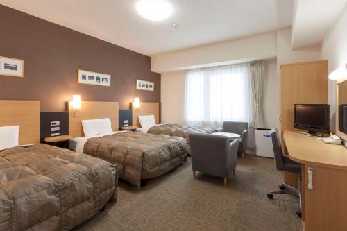 um quarto de hotel com duas camas e uma secretária em Comfort Hotel Naha Prefectural Office em Naha