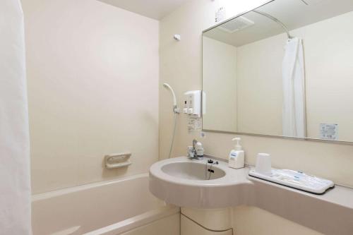 een witte badkamer met een wastafel en een spiegel bij Comfort Hotel Maebashi in Maebashi
