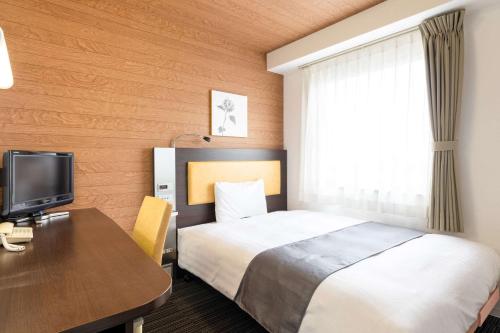 a hotel room with a bed and a desk at Comfort Hotel Kokura in Kitakyushu