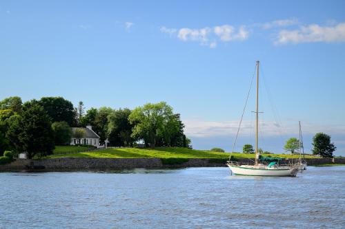 a sailboat in the water in front of a house at Idyllic, 5 Star Family Home with Panoramic Views, Kinvara on the Wild Atlantic Way in Kinvara