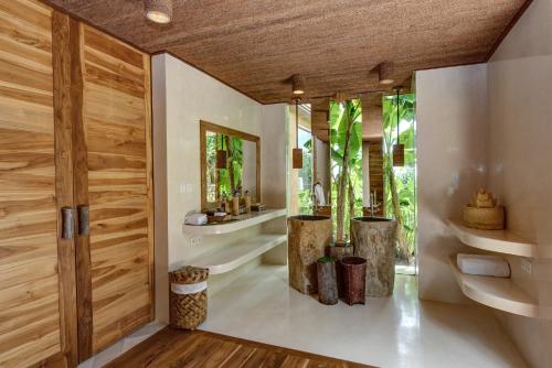 a pivot door in a bathroom with plants at NIHI Sumba - 50 Best Hotels of the World in Watukarere