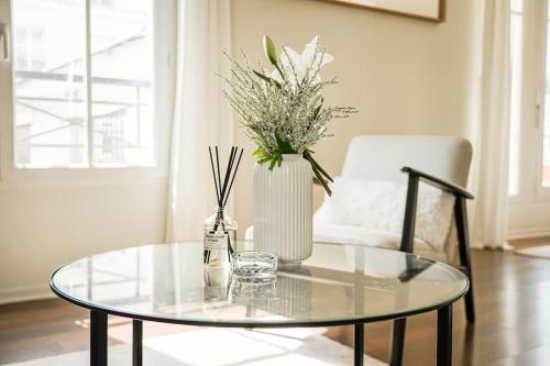 une table en verre avec un vase de fleurs et une chaise dans l'établissement Magical Résidence, Le Cour Royal near Disneyland Paris, just 5 min away !, à Chessy