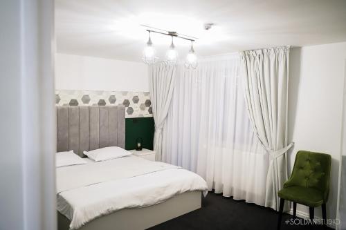 - une chambre avec un lit blanc et une chaise verte dans l'établissement La Codrii Cajvanei, 