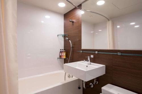 東京的住宿－東京東神田舒適酒店，一间带水槽、浴缸和镜子的浴室