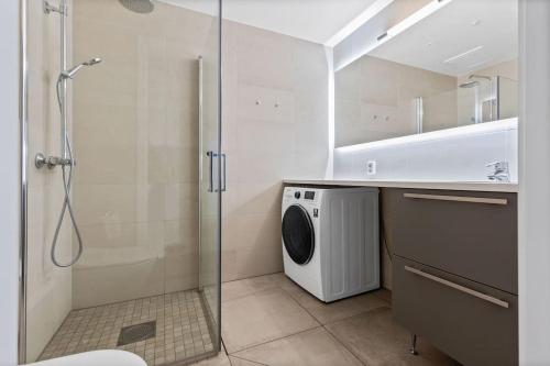 a bathroom with a shower and a washing machine at Superb apartment by Opera house in Oslo