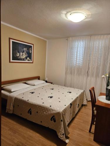 a bedroom with a bed and a table and a window at Apartman Bruna in Novigrad Istria