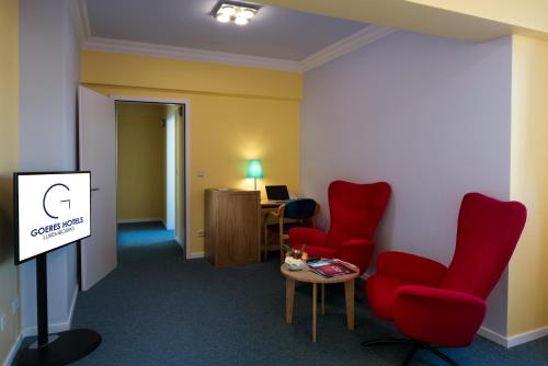 - une salle d'attente avec des chaises rouges et une table dans l'établissement Hotel Parc Belle-Vue, à Luxembourg