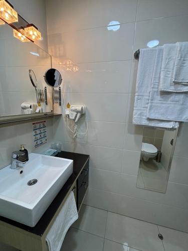 a white bathroom with a sink and a shower at Atrium in Sremska Mitrovica
