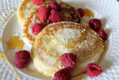 two pancakes with raspberries and syrup on a plate at Mallard Grange B&B in Ripon