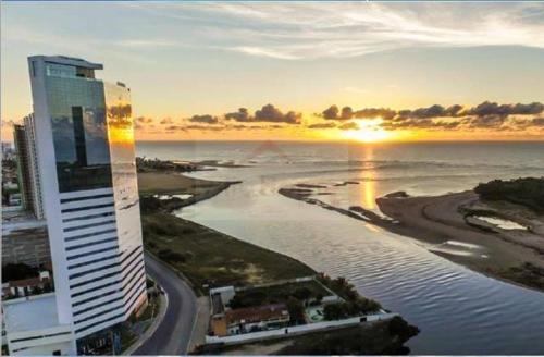 a tall building next to a beach with the sunset at Recife Infinity Pool - VIP in Recife