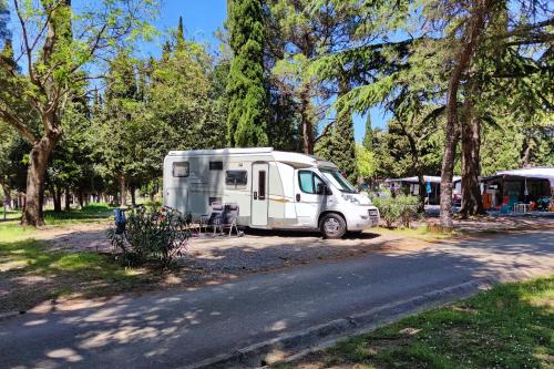 a white truck parked next to a road with trees at Camping Adria Ankaran - Pitches in Ankaran