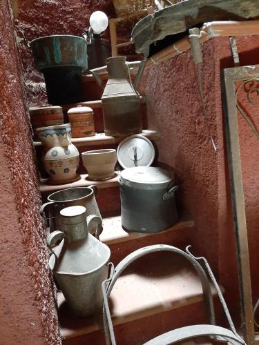 a shelf with various pots and pans and a clock at Al Palmento in Galati Mamertino