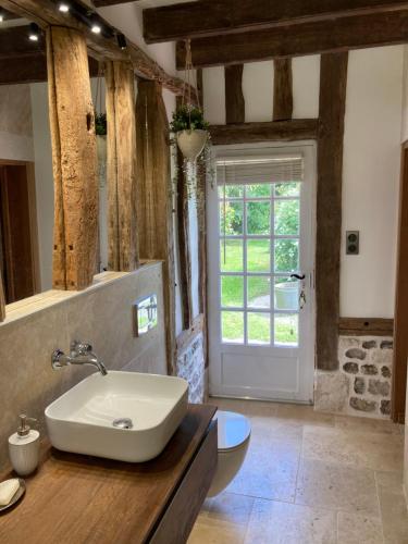 une salle de bain avec un lavabo et des toilettes et une fenêtre dans l'établissement La chaumière, à La Haye-Aubrée