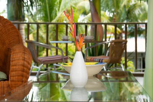 a glass table with a white vase with flowers in it at The Rusty Pelican in La Gaulette