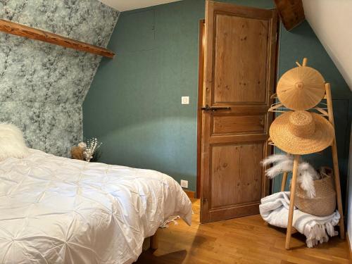 une chambre avec un lit et un chapeau sur une étagère dans l'établissement La chaumière, à La Haye-Aubrée