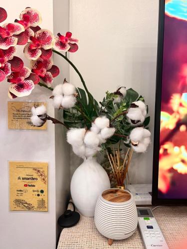 a white vase with flowers in it on a table at SMDC Green 2 Staycation, The Traditional & Modern Fusion Condo in Pasong Bayog