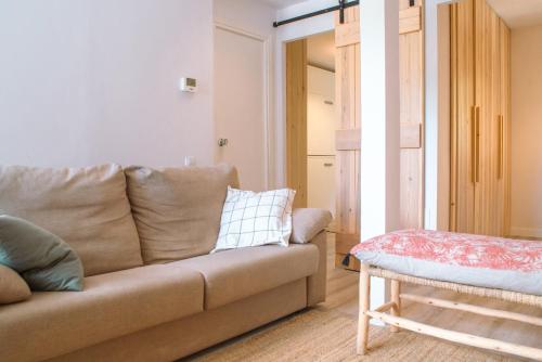 a living room with a couch and a stool at Apartamento en Formigal luminoso con balcón y vistas in Formigal