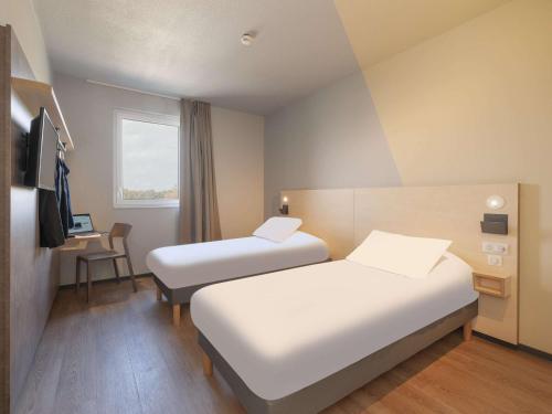 um quarto de hotel com duas camas e uma secretária em Ibis Budget Mont De Marsan em Mont-de-Marsan