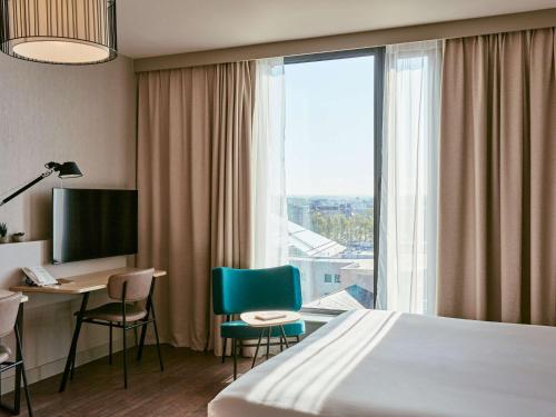 um quarto de hotel com uma cama, uma secretária e uma janela em Aparthotel Adagio Glasgow Central em Glasgow