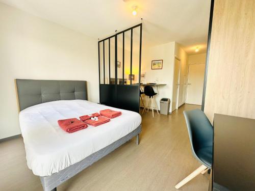 - une chambre avec un lit et 2 serviettes rouges dans l'établissement Studio 13 min plage - Parking - Ménage & Linge inclus, à La Rochelle