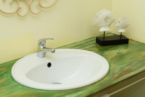 a white sink in a bathroom with two trophies at The Rusty Pelican in La Gaulette