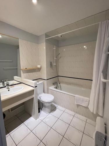 W łazience znajduje się toaleta, wanna i umywalka. w obiekcie Hôtel Michelet Plage w mieście Soulac-sur-Mer