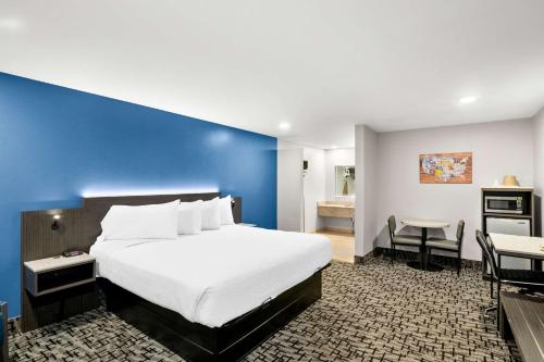 - une chambre avec un grand lit et un mur bleu dans l'établissement Econo Lodge Bethel - Danbury, à Bethel