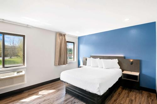 a bedroom with a large bed and a blue wall at Econo Lodge Bethel - Danbury in Bethel