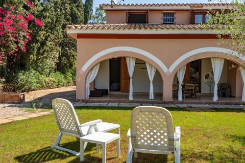 two chairs and a table in front of a house at Villa Girasole - Calice Apartment in Pula