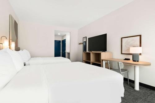 a hotel room with two beds and a desk and a tv at Spark by Hilton Lancaster Dutch Country in Lancaster