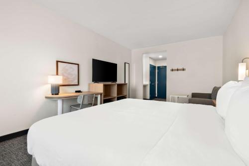 a hotel room with a white bed and a tv at Spark by Hilton Lancaster Dutch Country in Lancaster