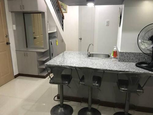 - une cuisine avec un évier et quatre tabourets de bar dans l'établissement Loft Style Condo Unit in Makati with Netflix WIFI, à Manille