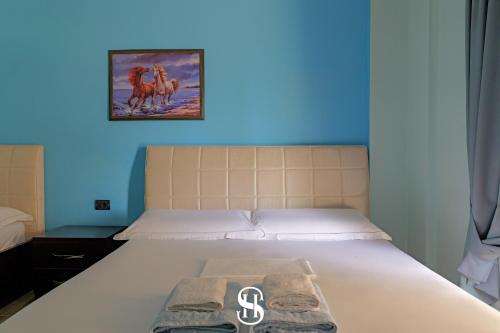 a bed in a room with a blue wall at Sala's Boutique Hotel in Sarandë