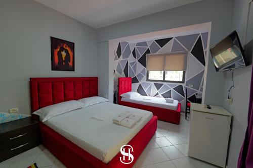 a bedroom with two beds and a tv in it at Hotel SALA in Sarandë