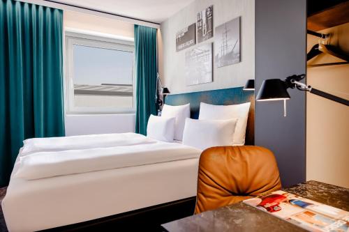 Habitación de hotel con 2 camas y escritorio en Motel One Hamburg am Michel en Hamburgo