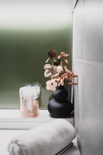 a black vase with flowers on a shelf next to a refrigerator at Butique Apartman Grand in Balatonlelle