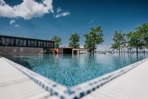 basen z niebieską wodą przed budynkiem w obiekcie Butique Apartman Grand w mieście Balatonlelle