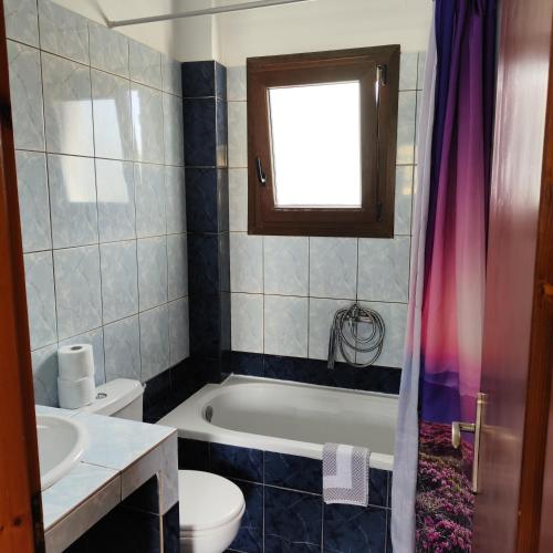 a bathroom with a tub and a toilet and a sink at Ekaterini Apartments in Gouvia