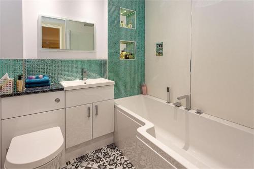 a bathroom with a tub and a toilet and a sink at Orchard Brae in Edinburgh