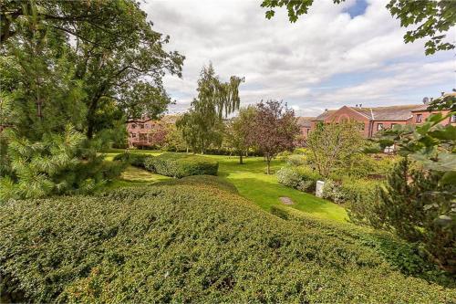 a garden with bushes and trees and buildings at Orchard Brae in Edinburgh