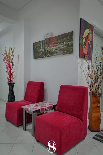two red chairs and a table in a room at Hotel SALA in Sarandë